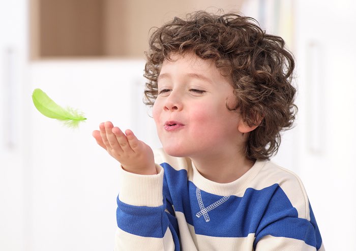 kind_pustet_feder_spielerisch_atemuebung